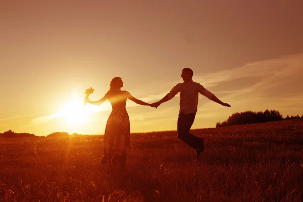 Young happy couple jumping on sunset — Stock Photo, Image