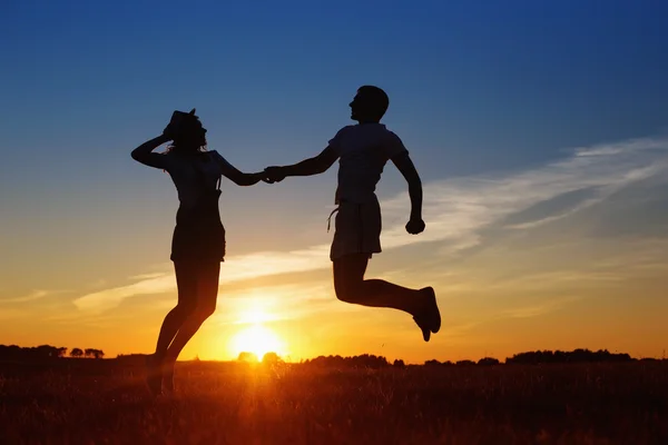 Young happy couple jumping on sunset — Stock Photo, Image