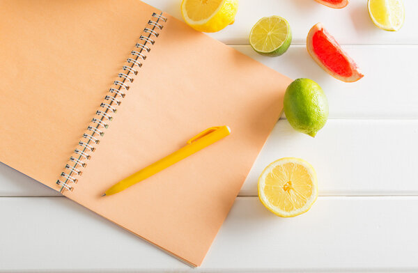 Цитрусовые с ноутбуком на белом деревянном столе
