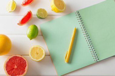 Beyaz ahşap masa üstünde defter ile narenciye