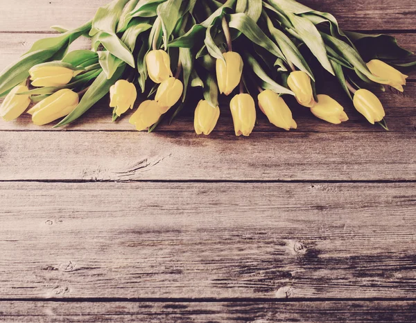 Tulipanes amarillos sobre fondo de mesa de madera — Foto de Stock