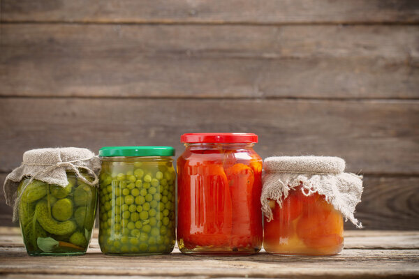 Jars with pickled vegetables on wooden background