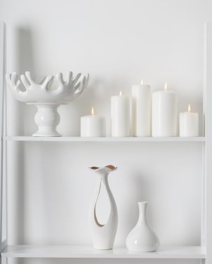 Beyaz bir rafa yanan beyaz mumlar