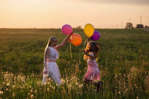Щасливі жінки і дівчина стрибає з повітряними кулями на відкритому повітрі — стокове фото