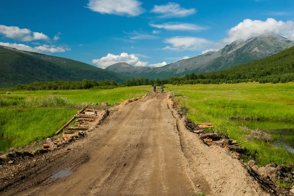 Bicycle tourists on the bumpy road — Stock Photo, Image