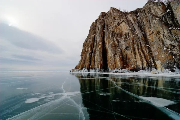在冰冻的湖面上的岩石峭壁 — 图库照片