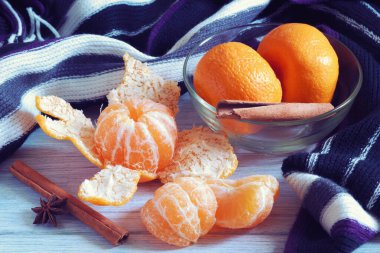 Kış mevsiminde beyaz ahşap masada sıcak eşarplı mandalinalı meyveler.