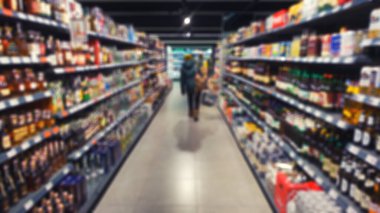 Süpermarkette alışveriş yapan ve raflarda çeşitli yiyecekler bulunan koridora odaklı olmayan manzara. Soyut arkaplan için bulanık fotoğraf.