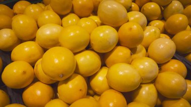 Meyve pazarı vitrininde bir yığın sarı limon.