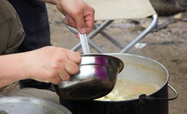 Kamp ateşi üzerine çorba. Tencerede yiyecek ve eğlence