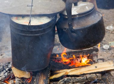 Kamp ateşi üzerine çorba. Tencerede yiyecek ve eğlence