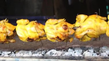 Whole chickens are roasted on a spit
