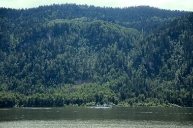 Tekne bir dağ gölü kıyısından geçiyor. Teletskoye Altai dağlık gölünde