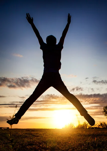 Homem feliz saltando ao pôr do sol — Fotografia de Stock