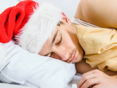 Santa Hat 'ta bir adam yakın planda yatağında uyuyor.