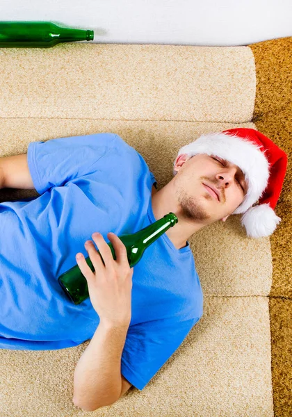 サンタ ハットの若い男がビールとソファで寝ている — ストック写真