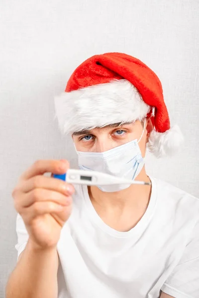 Sick Young Man Santa Hat Και Μάσκα Γρίπης Δείχνουν Ένα — Φωτογραφία Αρχείου