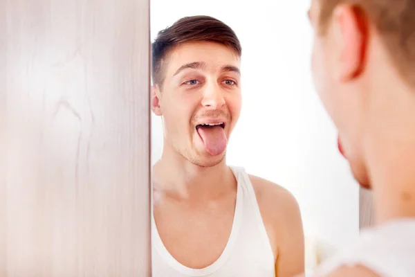 Mladý Muž Hledající Reflexi Zrcadle Ukazující Jazyk — Stock fotografie