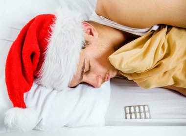 Santa Hat 'taki genç adam bir hapla yatakta uyuyor.