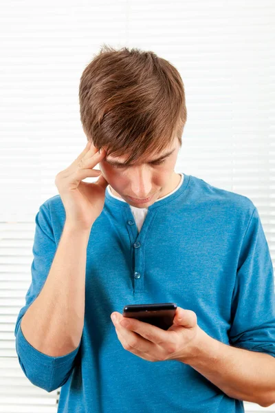 Troublé Jeune Homme Avec Téléphone Portable Pense Dans Une Pièce — Photo