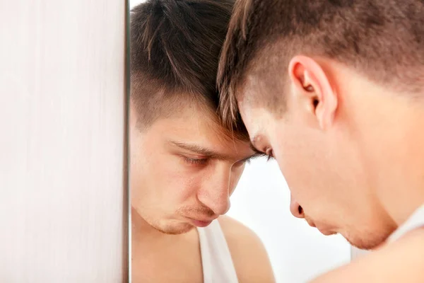 Sad Young Man near in the Mirror in the Room