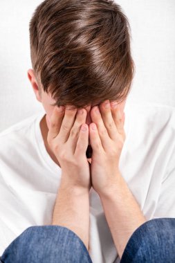 Beyaz Duvar 'ın yanındaki üzgün genç adam. Yakın plan.