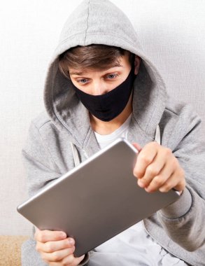 Genç adam, Beyaz Duvar 'ın yanındaki Tablet Bilgisayarda bir video oyunu oynuyor.