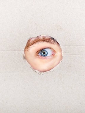 Kartondaki bir delikten bakan göz. Yakın plan.
