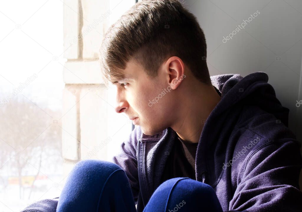 Sad and Pensive Young Man by the Window in the Room