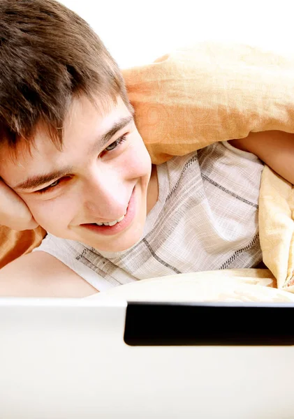 睡床时带着笔记本电脑的快乐青少年 — 图库照片