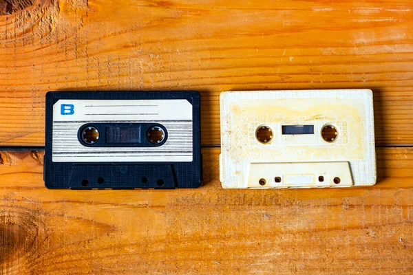 Two Old Audio Cassettes on the Wooden Planks Background closeup