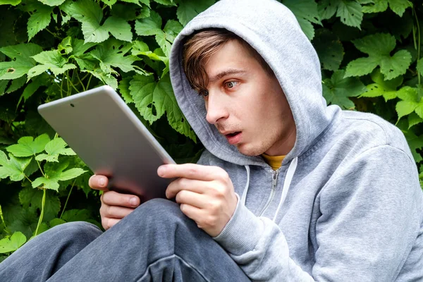 Surpreendido Jovem Com Computador Tablet Fundo Folhas Verdes Livre — Fotografia de Stock