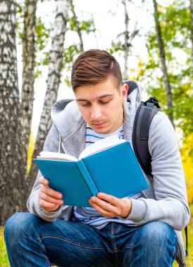 Genç adam ormanda tek başına kitap okudu.