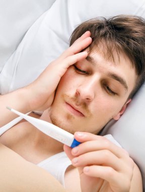 Evde Yatakta Bir Termometre ile Hasta Genç Adam
