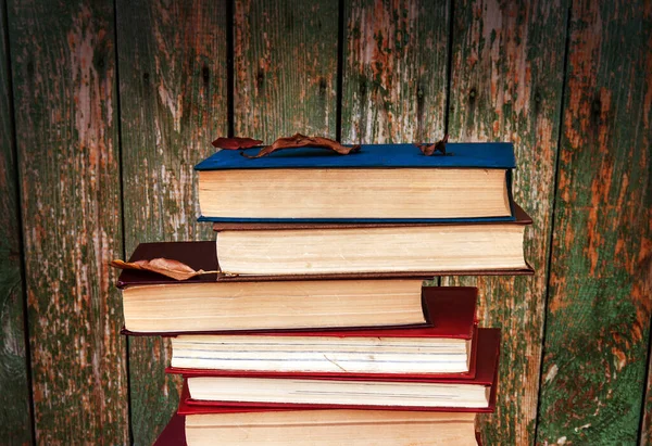 旧木造の壁の背景の本の山 — ストック写真