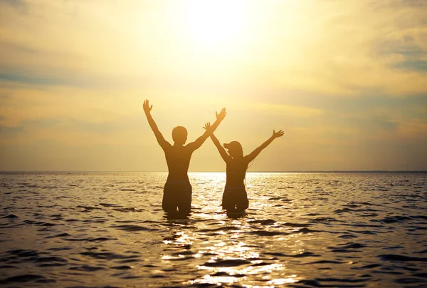 海の中で手を上げて幸せなカップルシルエットのトーン写真 — ストック写真