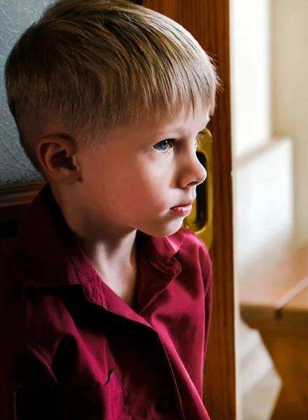 悲しい小さな男の子が部屋の肖像画のクローズアップに立つ — ストック写真