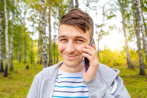 Šťastný Mladý Muž Mobilním Telefonem Podzimním Parku — Stock fotografie