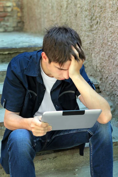 Грустный подросток с планшетным компьютером — стоковое фото