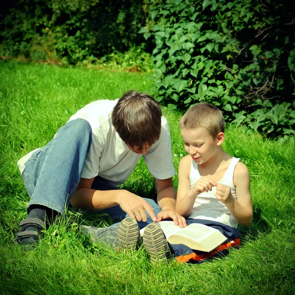 Adolescente e criança lê um livro — Fotografia de Stock