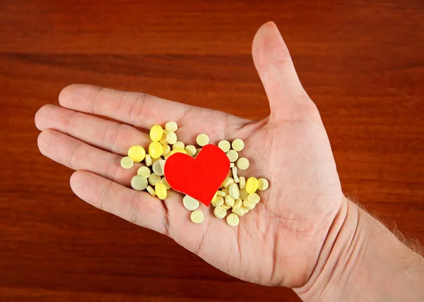 Comprimidos e forma do coração na mão — Fotografia de Stock
