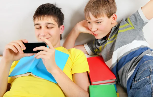 Hermanos con un libro y un celular —  Fotos de Stock