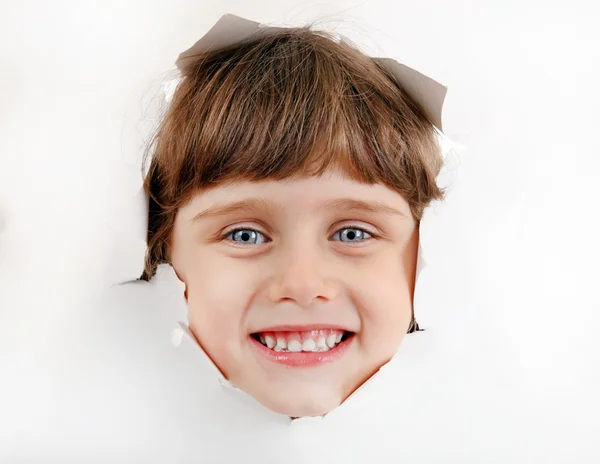 Pequeña cara de niña a través de un agujero de papel — Foto de Stock
