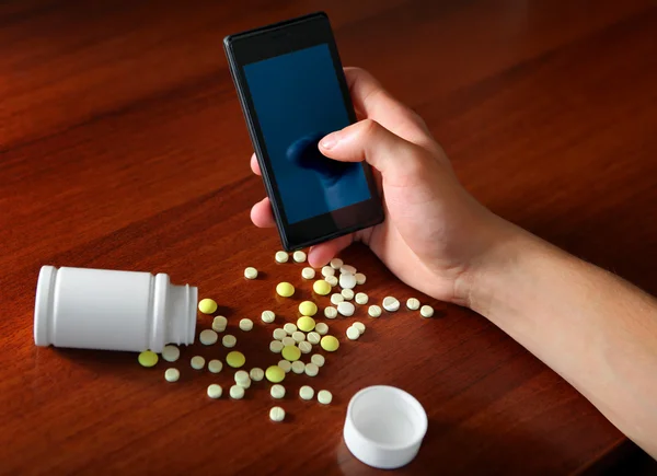 Persona con el teléfono celular y las píldoras — Foto de Stock