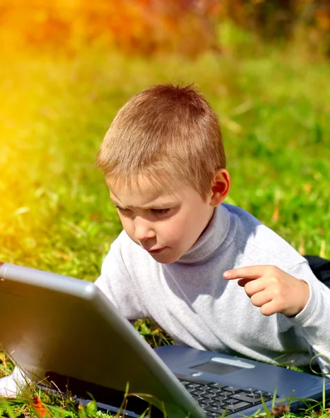 Niño con ordenador portátil al aire libre — Foto de Stock