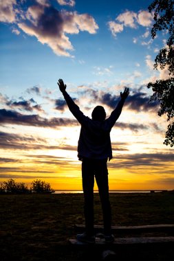 Happy Man Silhouette with Hands Up on the Sunset Background clipart