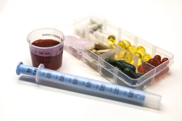 Diferentes píldoras, medicamentos, las píldoras en la caja para medicamentos primer plano con medicamentos con una jeringa sobre fondo blanco . — Foto de Stock