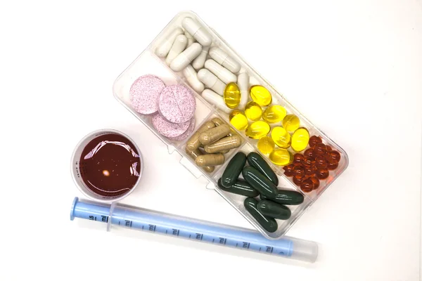 Diferentes píldoras, medicamentos, las píldoras en la caja para medicamentos primer plano con medicamentos con una jeringa sobre fondo blanco . —  Fotos de Stock