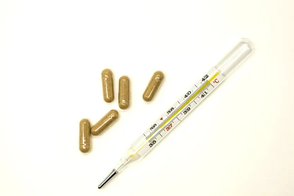 Termómetro médico de mercurio viejo con pastillas de primer plano sobre fondo blanco — Foto de Stock