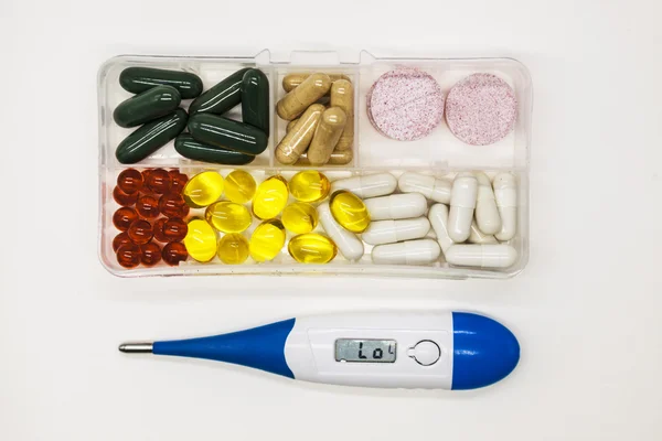 Diferentes píldoras, medicamentos, las píldoras en la caja para las drogas primer plano con termómetro sobre fondo blanco . —  Fotos de Stock